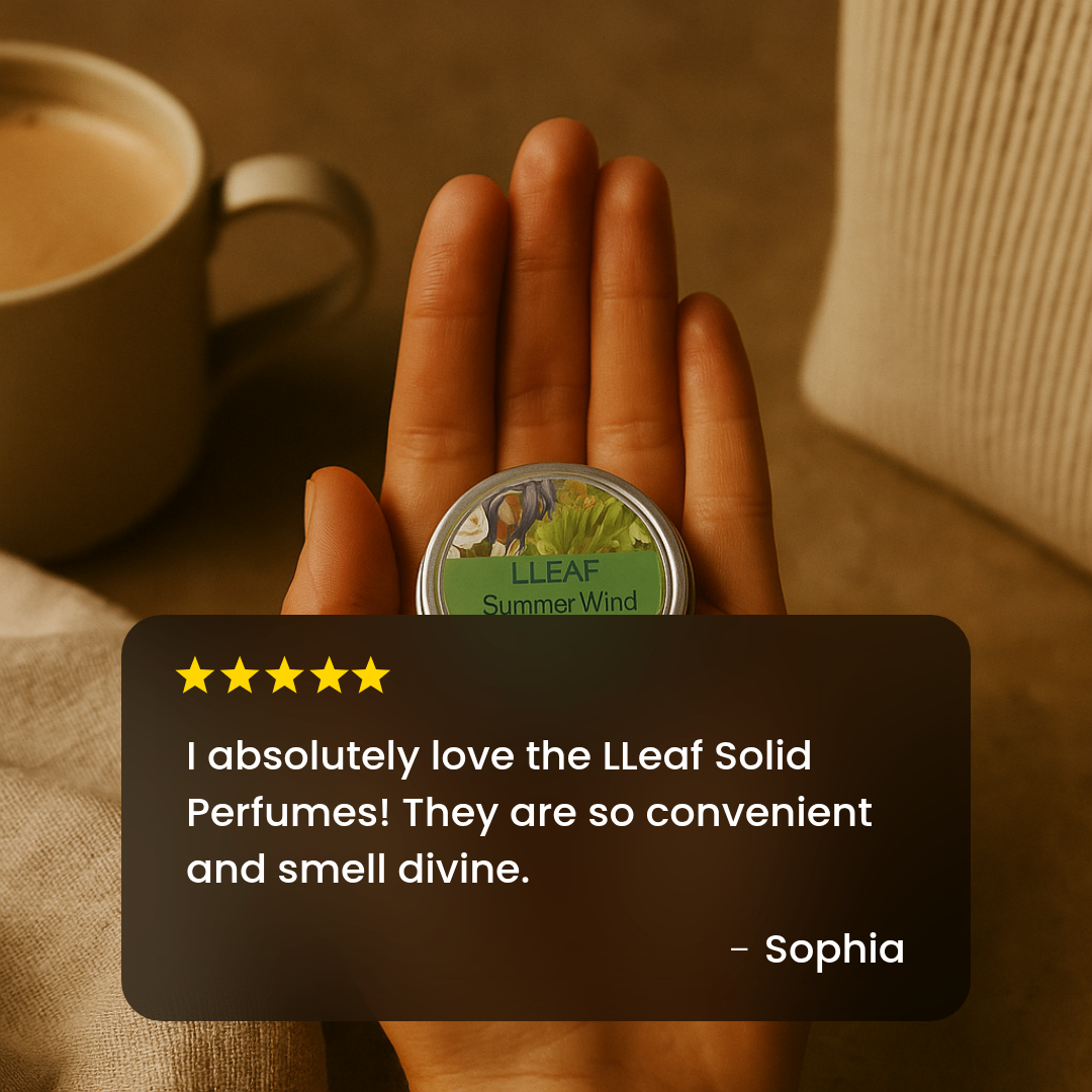 Hand holding a LLEAF solid perfume tin with a cup of coffee in the background
