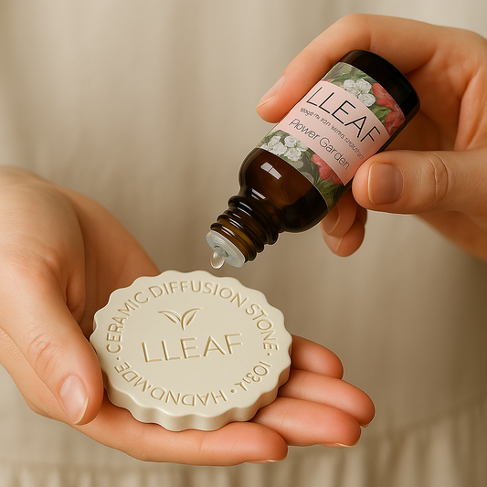 Hand pouring essential oil into a ceramic diffuser stone with LLEAF branding.