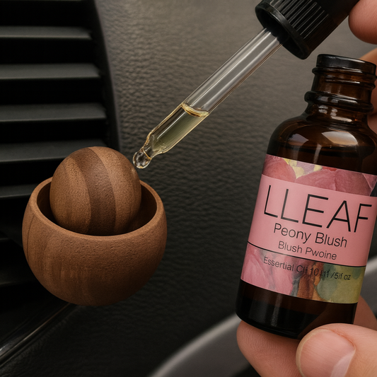 Hand holding a bottle of LLEAF Peony Blush essential oil with a dropper over an air vent.