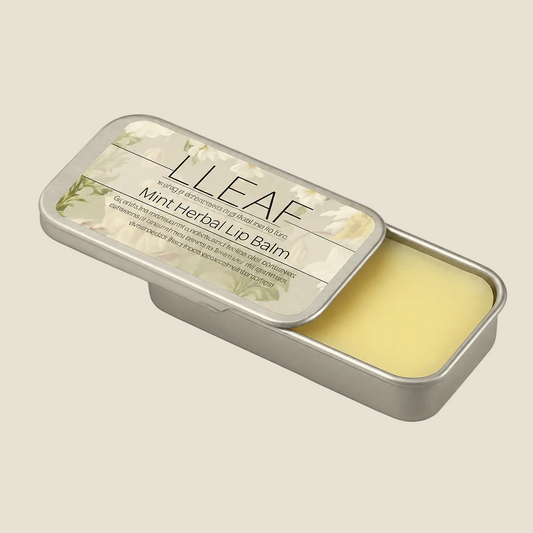A silver metal tin of LLEAF Mint Herbal Lip Balm, with the lid partially open to reveal the pale yellow balm inside, set against a solid beige background.