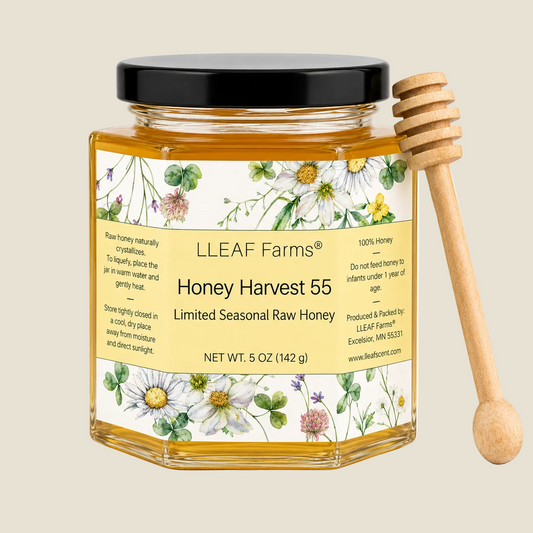 A glass jar of LLEAF Farms Honey Harvest 55 raw honey with a black lid and a wooden honey dipper, set against a clean white background.