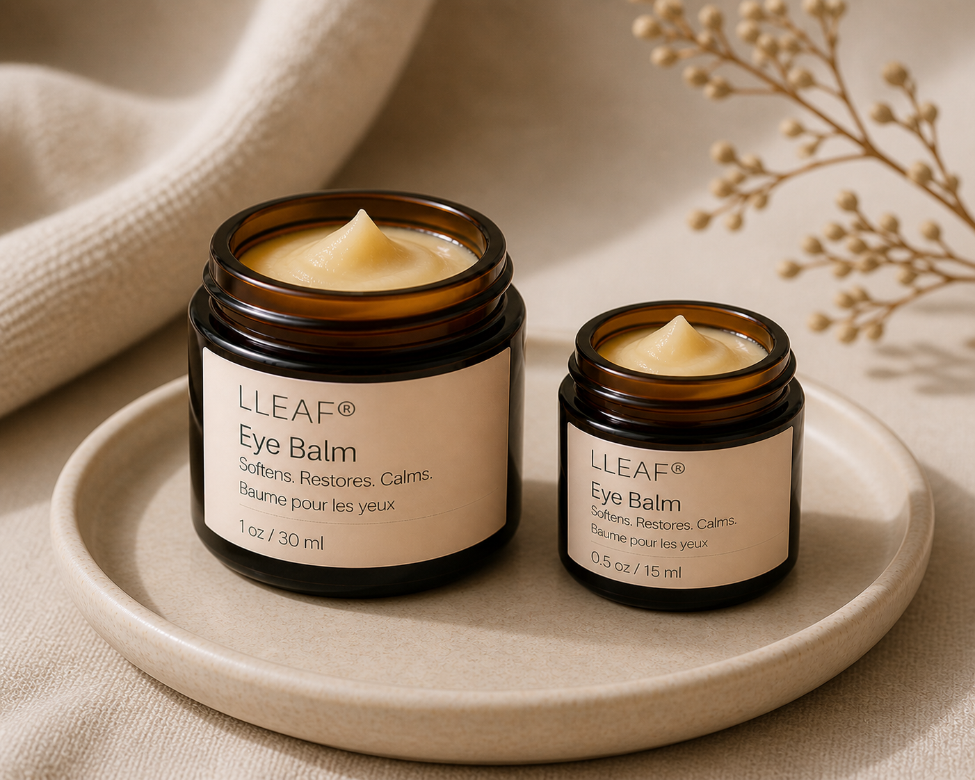 Two jars of LLEAF Eye Balm on a beige plate with a neutral background