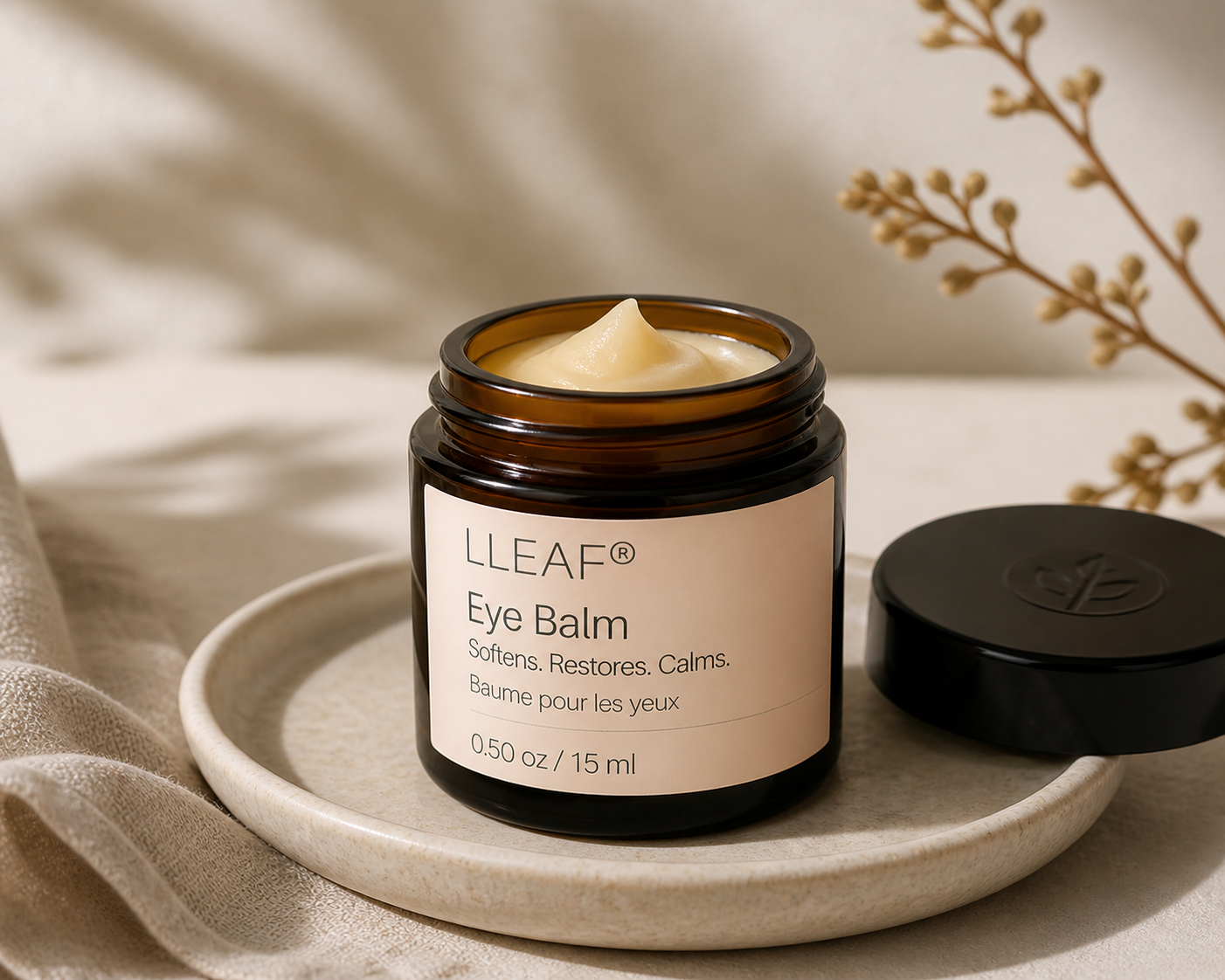 LLEAF Eye Balm jar on a beige plate with a neutral background