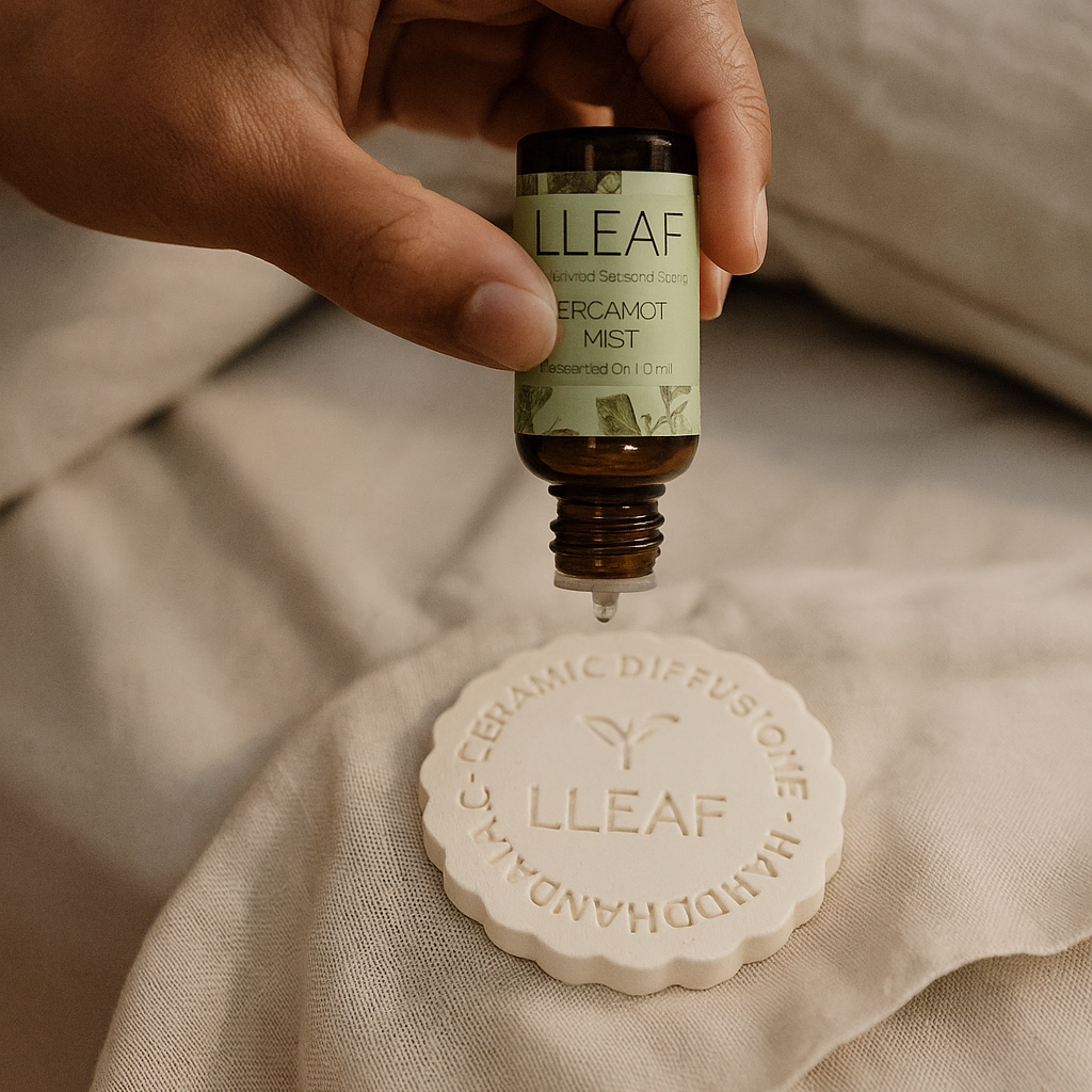 Hand holding a bottle of LLEAF essential oil above a soap bar on a beige fabric background